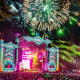 Colorful Electric Forest festival scene with lights, stage design, and people moving through the grounds.