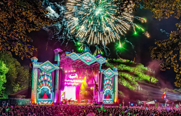 Electric Forest Is Built For Wandering 4 Colorful Electric Forest festival scene with lights, stage design, and people moving through the grounds.