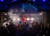 A DJ performs beneath blue-lit stage art as a crowd dances at Sonic Springs Festival.