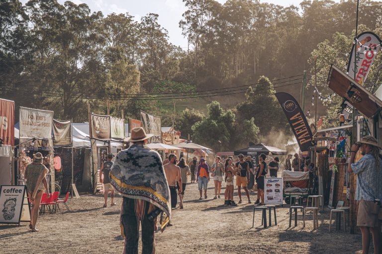 Festival attendees walking between food and market stalls at Earth Frequency.