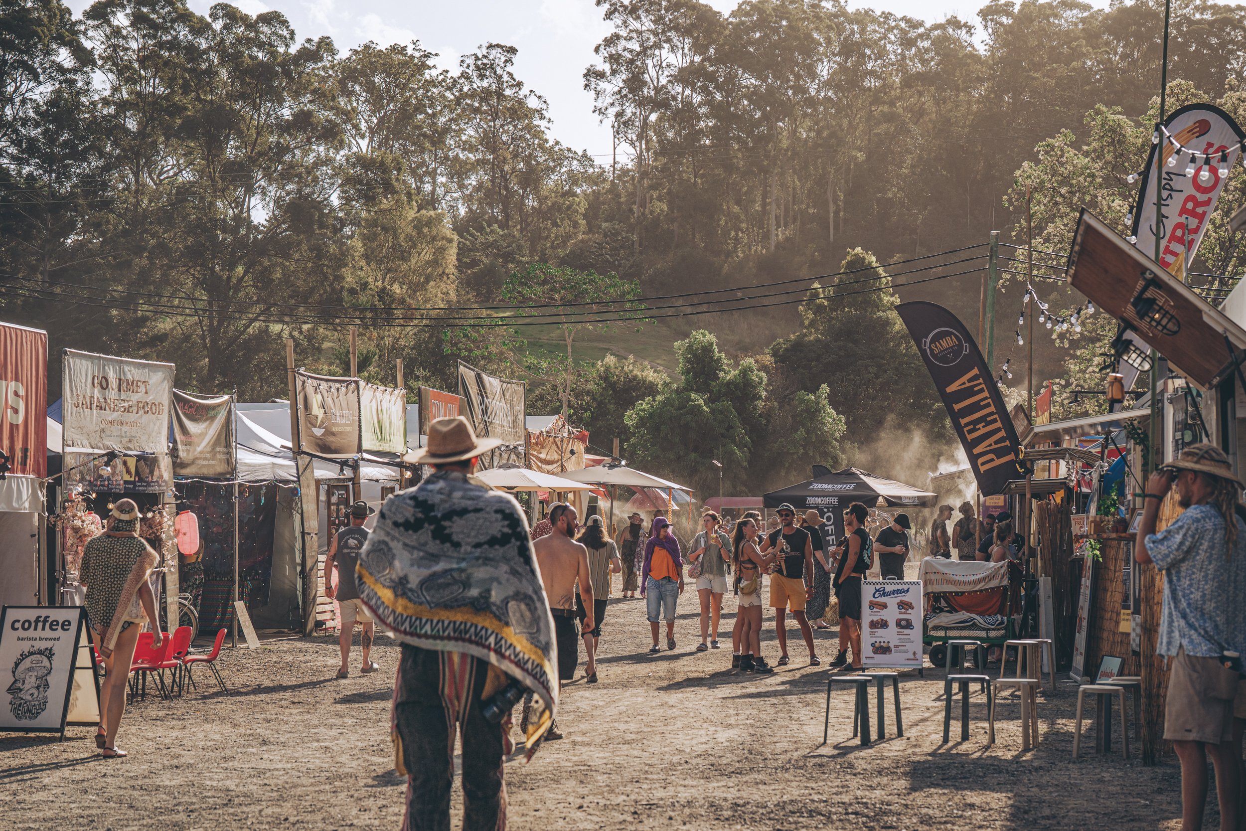 Festival attendees walking between food and market stalls at Earth Frequency.