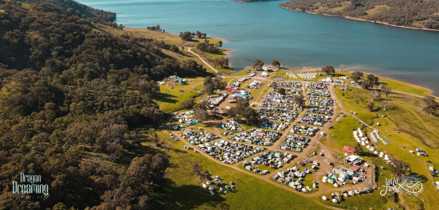 Dragon Dreaming '26 Survival Guide 2 Aerial view of a lakeside festival campground