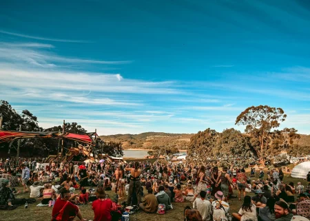Festival attendees gather on a hillside beside a lake