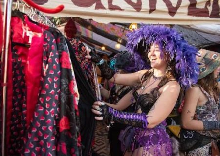 Festival attendee browsing patterned clothing at a Hulaween market stall