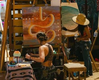 Artists working in a shaded outdoor festival vendor space