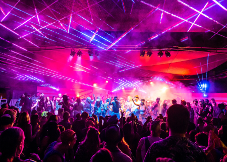 Crowd and performers under pink and purple laser lights