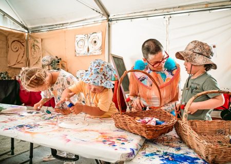 Children and a facilitator make art together in a Dragon Dreaming workshop tent.