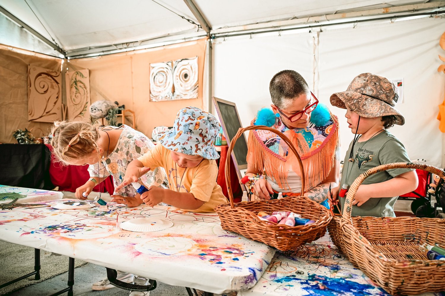 Children and a facilitator make art together in a Dragon Dreaming workshop tent.