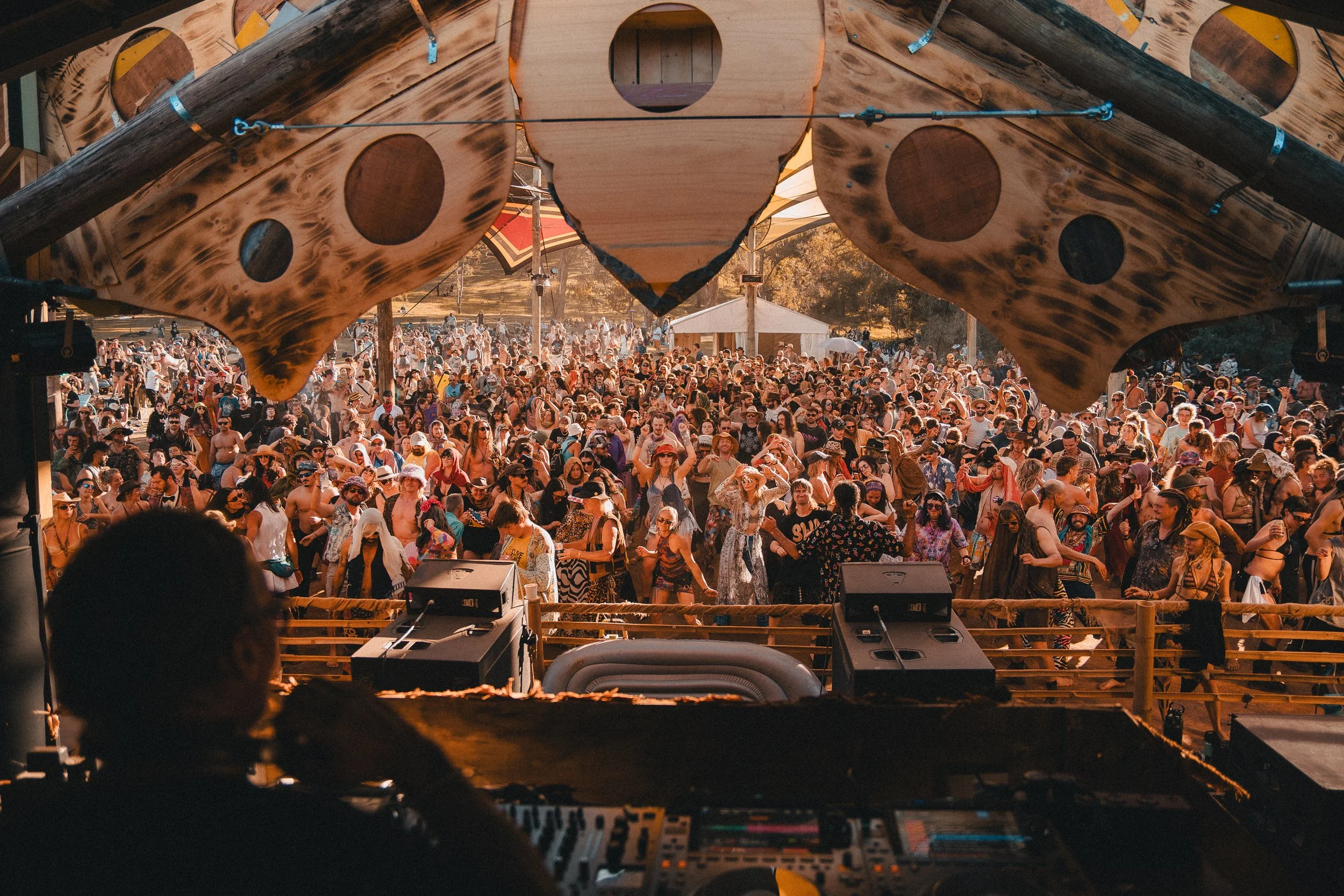 Large wooden owl sculpture above a daytime festival stage