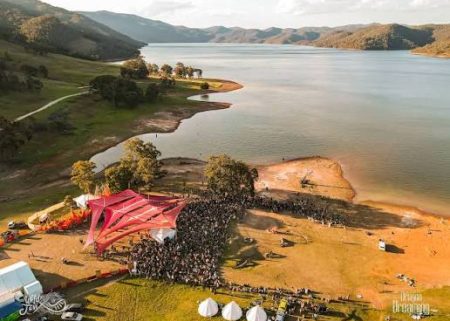 Aerial view of a lakeside festival stage and crowd
