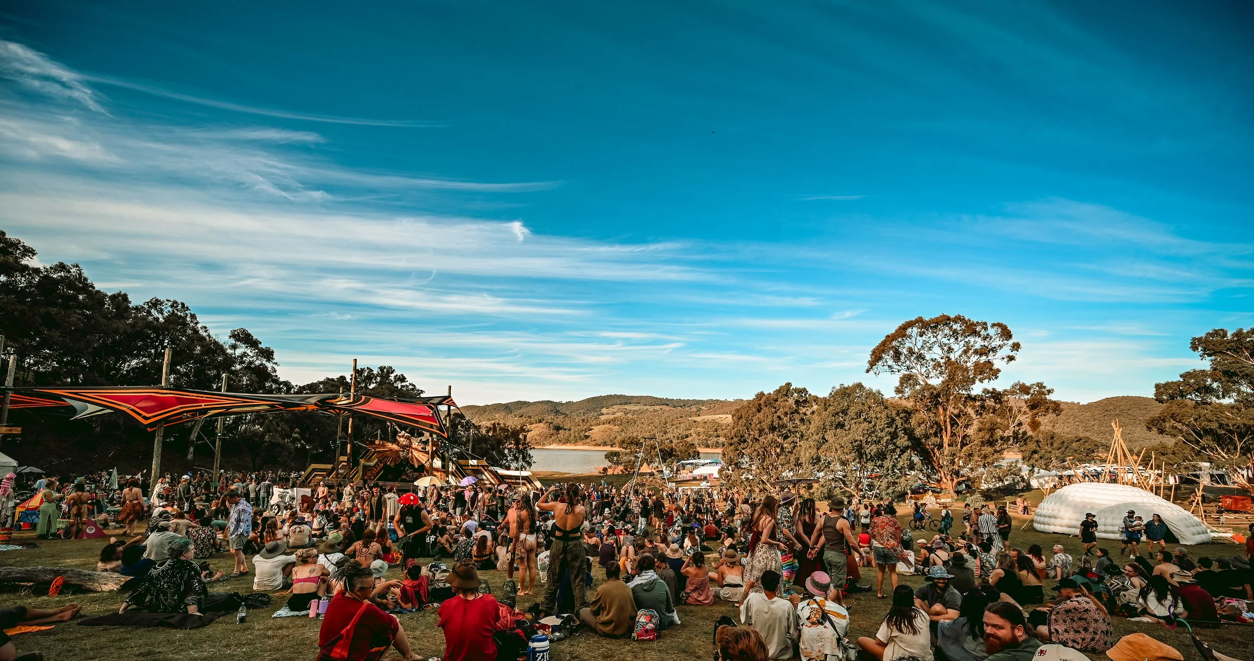 Festival attendees gather on a hillside beside a lake