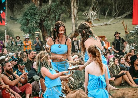 Participants in blue costumes take part in a community ceremony at Dragon Dreaming.