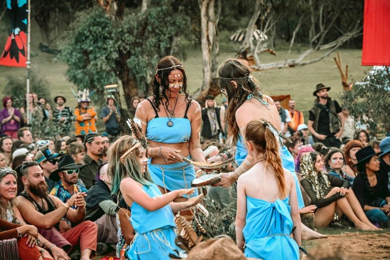 Participants in blue costumes take part in a community ceremony at Dragon Dreaming.