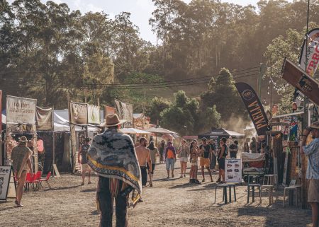 Festival attendees walking between food and market stalls at Earth Frequency.