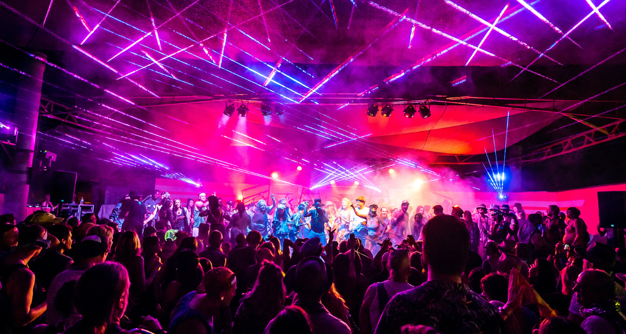 Crowd and performers under pink and purple laser lights