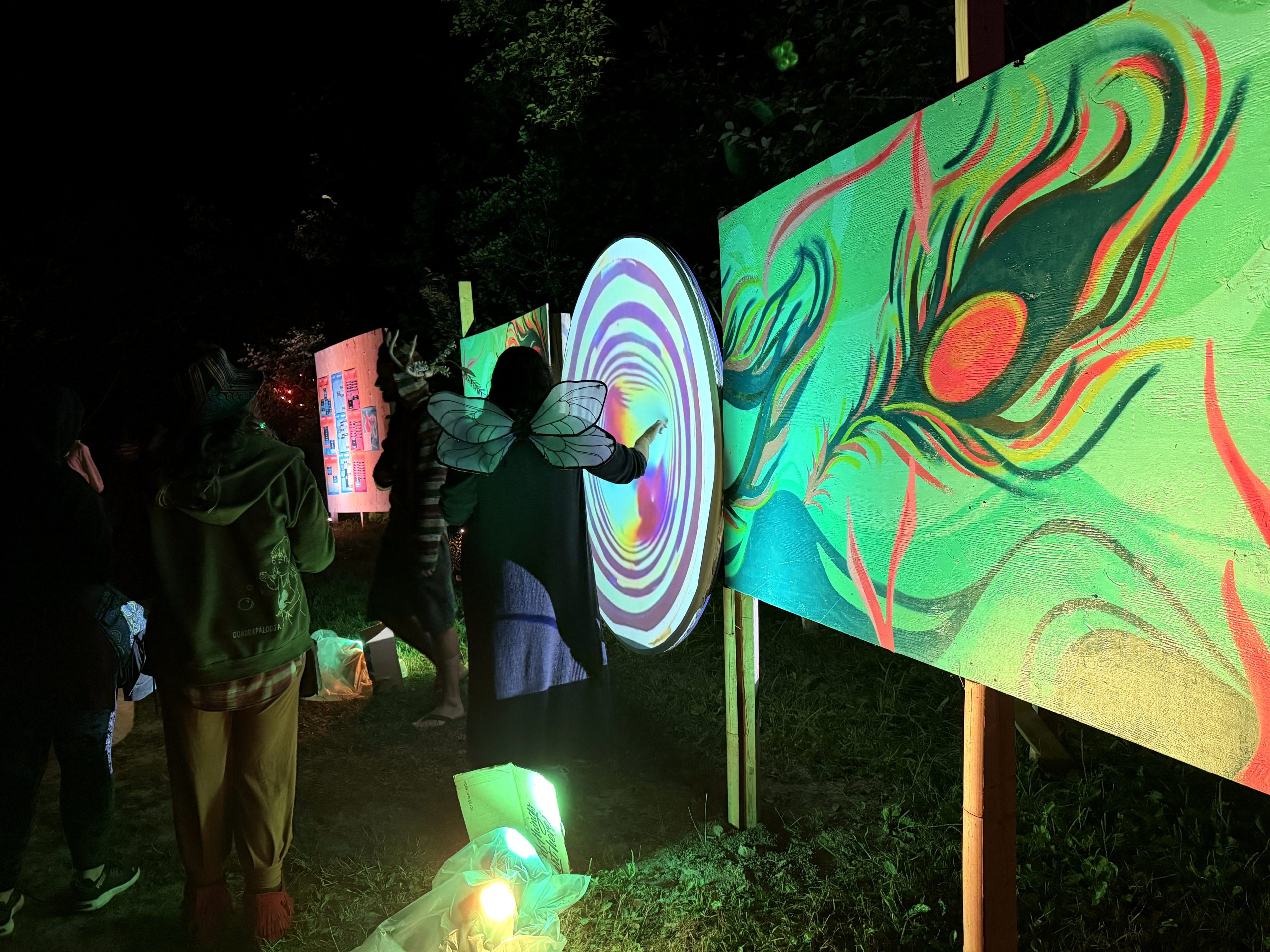 A World Worth Making 14 A visitor interacts with Micha Dahan’s circular installation beside illuminated paintings.