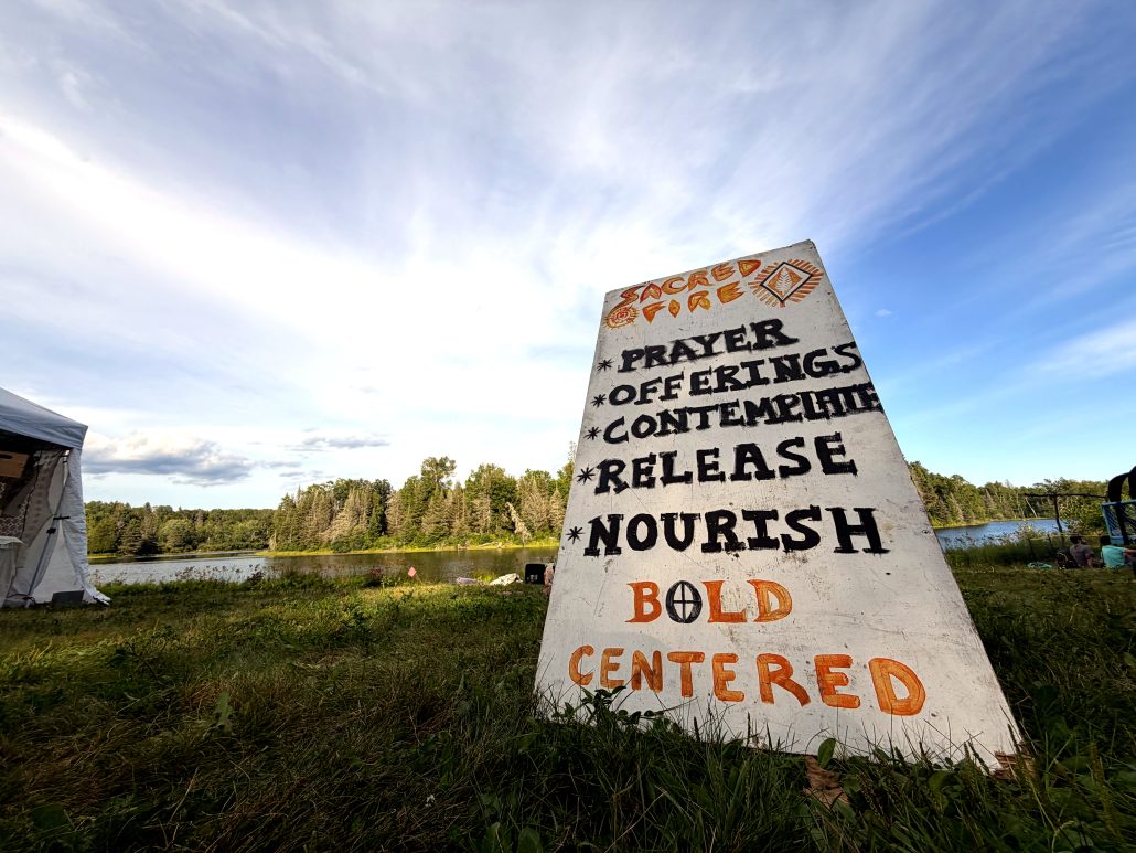 A painted offerings sign beside the river at Sonic Springs