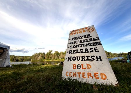 A painted offerings sign beside the river at Sonic Springs