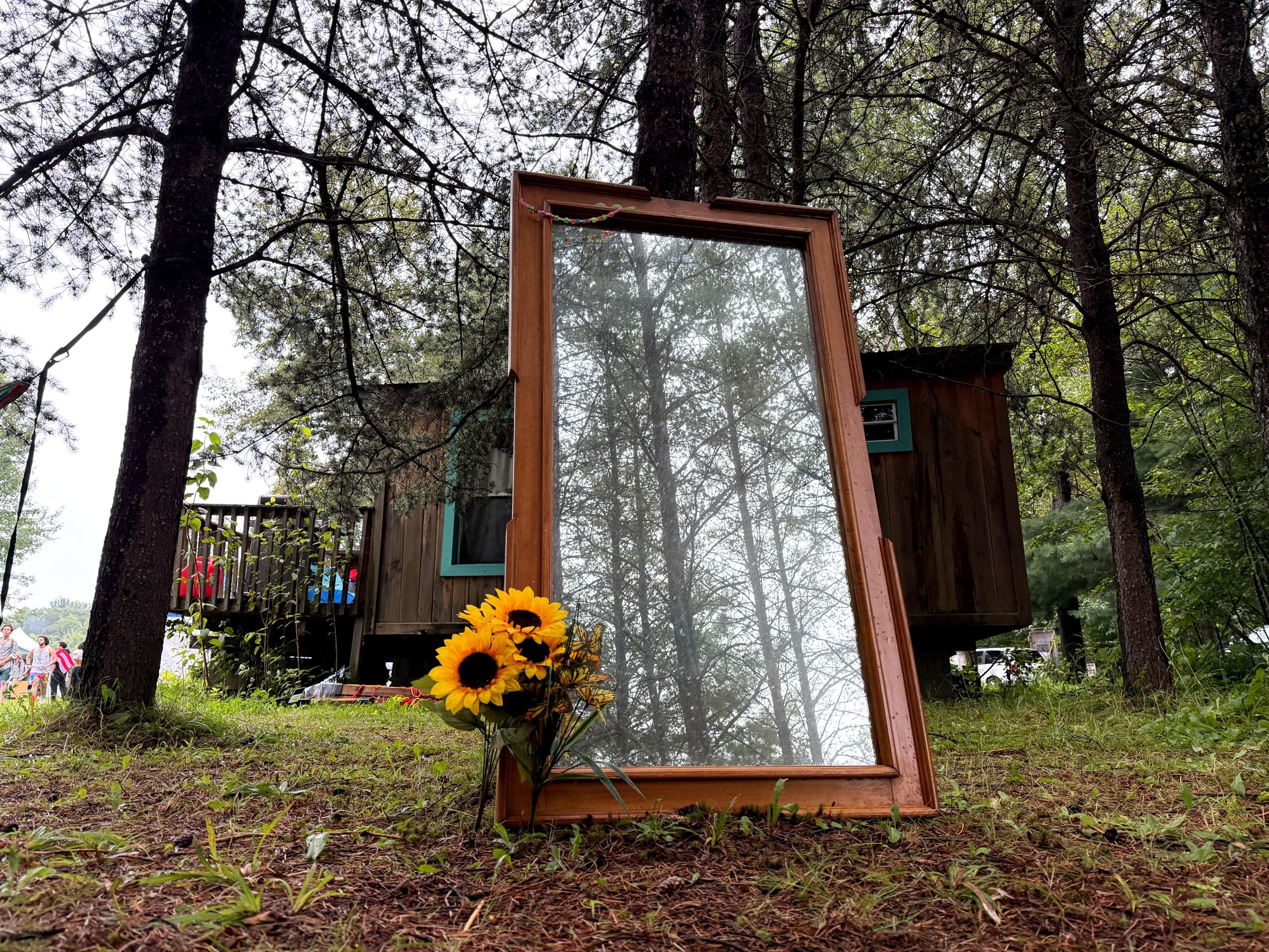 A World Worth Making 3 A framed mirror reflects the trees beside a forest cabin